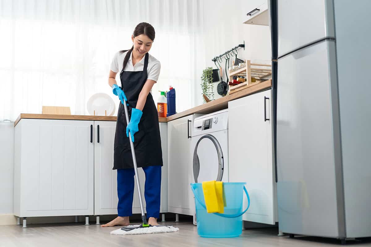 Asian active cleaning service woman worker cleaning in kitchen at home.