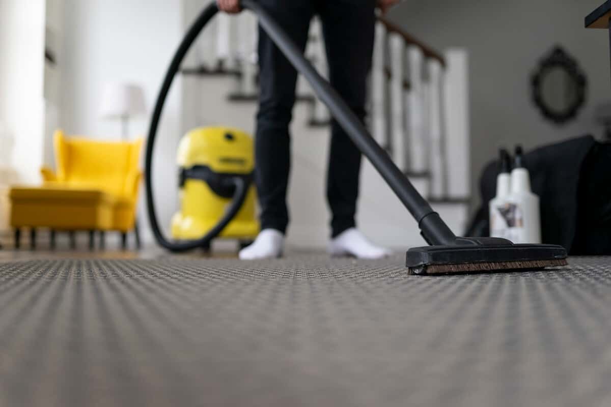 Man vacuuming the carpet in the room