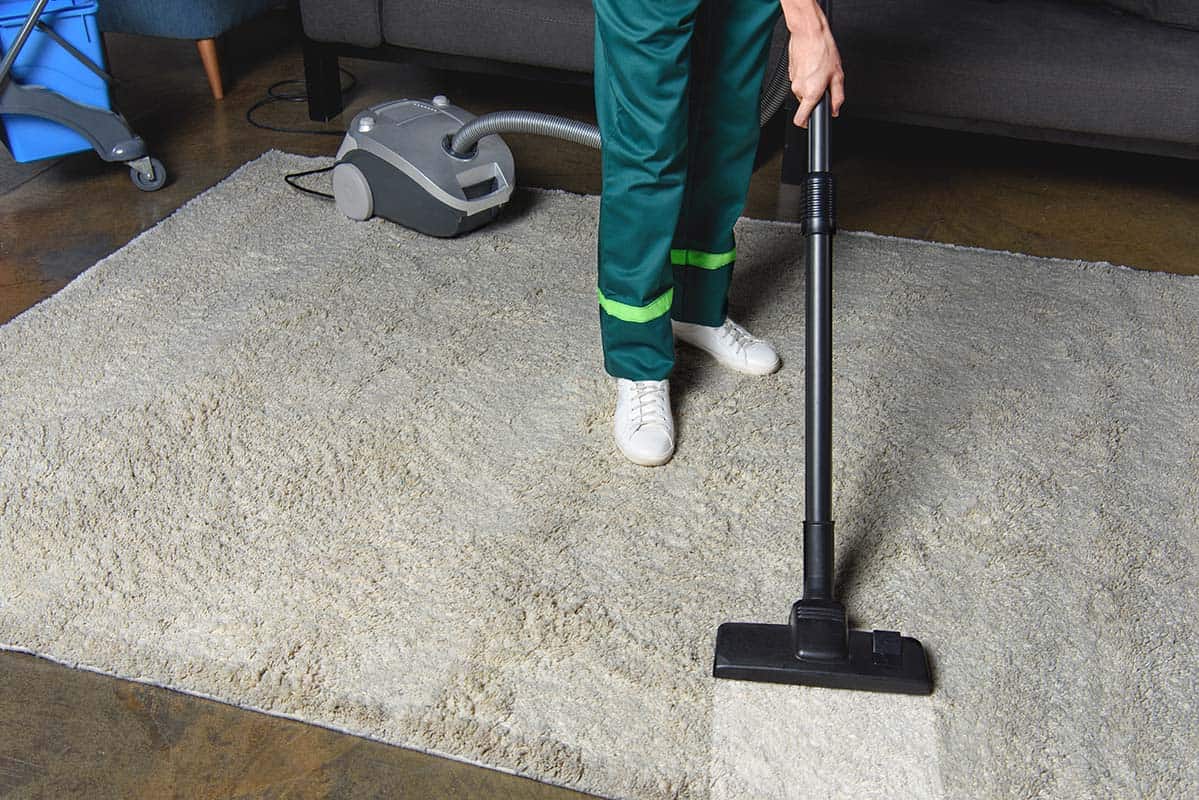 high angle view of professional cleaner using vacuum cleaner and cleaning white carpet in Bethnal Green