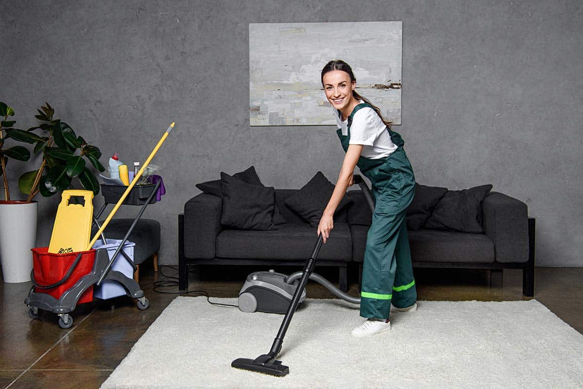 female carpet cleaner vacuuming a white carpet