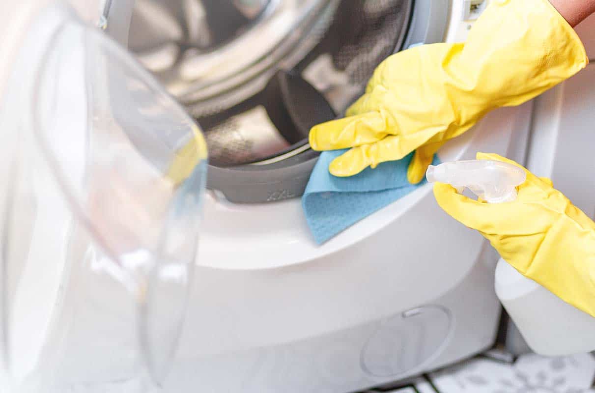 person cleaning inside of washing machine