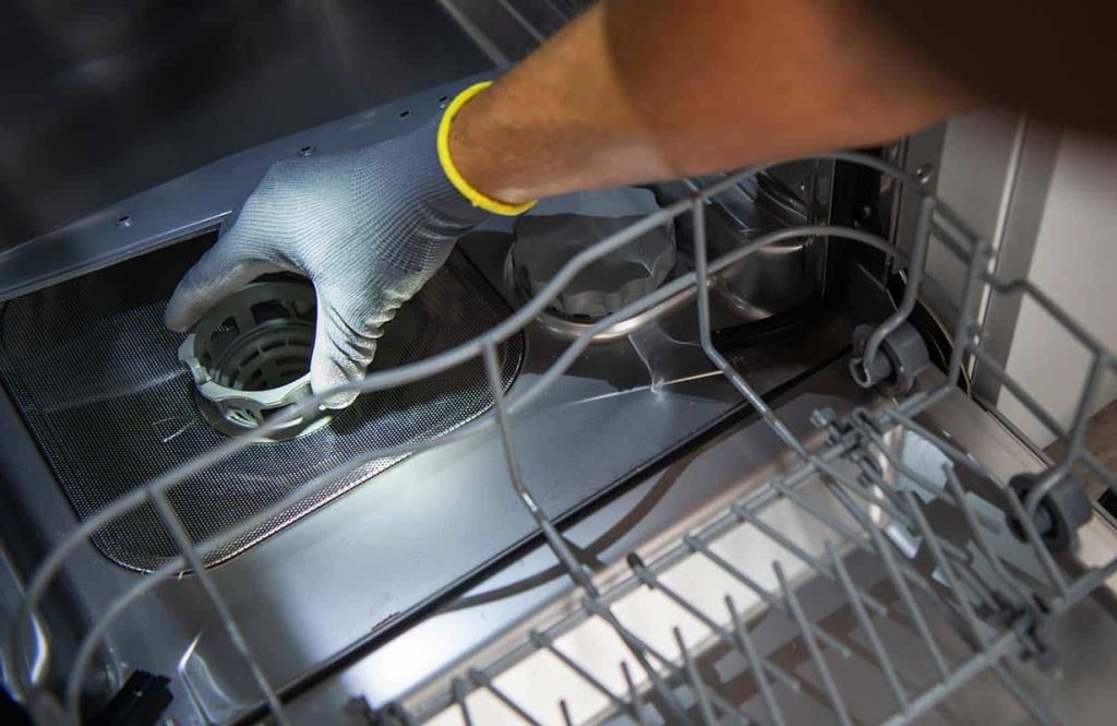 man cleaning filter of a dishwasher